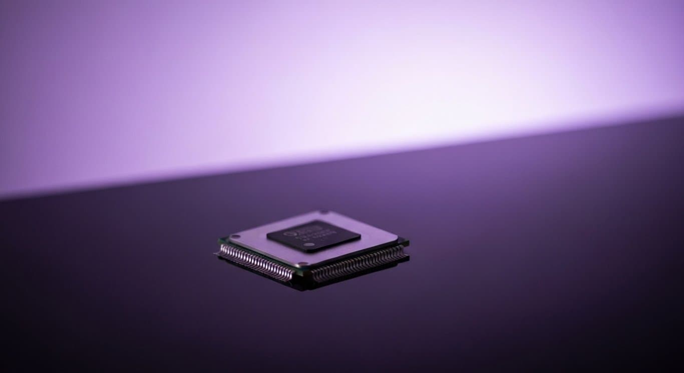 Silver semiconductor chip on reflective surface with a soft purple technology-themed background