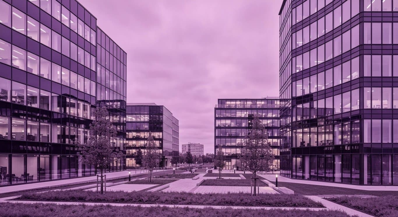 Modern office buildings in front of a cityscape with greenery and a purple hue