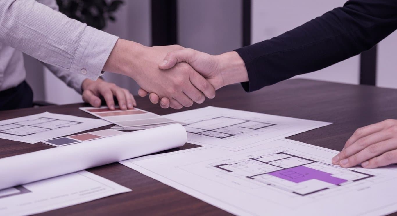 Hands shaking over paint sample in a modern home interior with architectural plans nearby